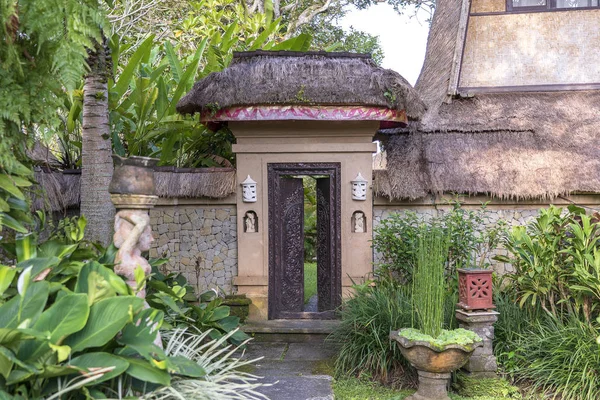 Trottoaren leder till en in i huset med balinesiska skulpturer i en tropisk trädgård, Island Bali, Indonesien — Stockfoto