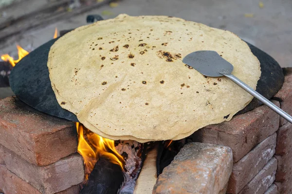Frau kocht traditionelles indisches Brot, große Chapati kochen auf offenem Feuer, Indien — Stockfoto