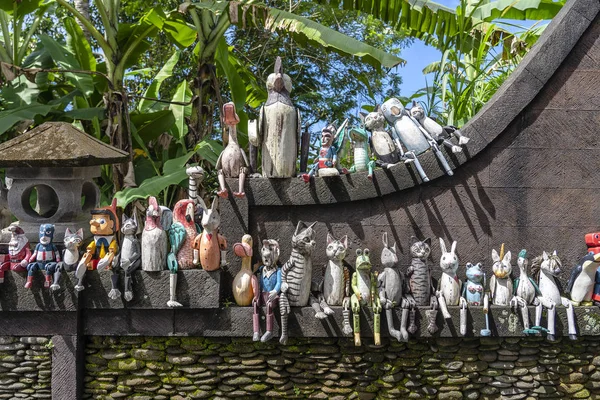 Old wooden souvenirs toys on the stone fence near the doll shop in Ubud, Bali island, Indonesia. Closeup