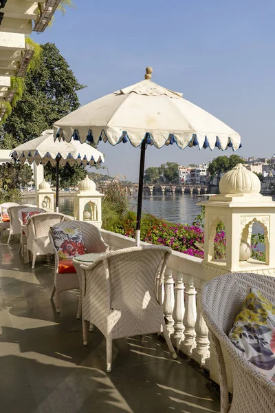 Tavolo e sedie in rattan sotto un ombrellone in un caffè di strada sulla riva vicino al lago di Udaipur, Rajasthan, India . — Foto Stock
