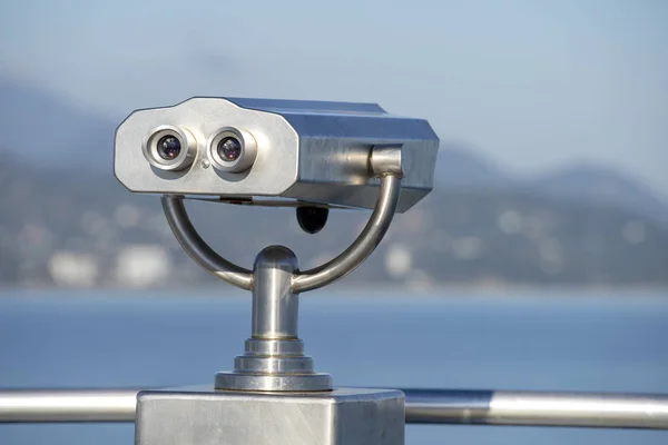 Binocular público na costa do mar, de perto. Moeda operado visualizador binocular no fundo turvo do pôr do sol e do mar — Fotografia de Stock