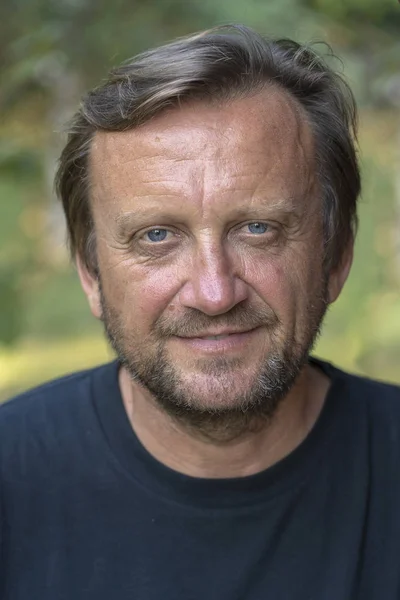 Portrait of a middle aged man resting on a background of green leaves in nature, closeup — Stock Photo, Image