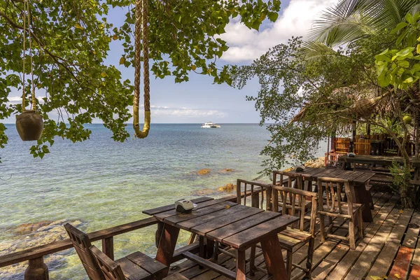 Mesa de madeira e cadeiras em café de praia vazio ao lado de água do mar. Ilha Koh Phangan, Tailândia — Fotografia de Stock