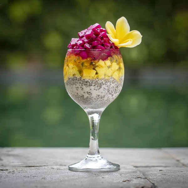 Budín de semillas de chía con fruta roja de dragón, fruta de la pasión, mango y aguacate en un vaso para el desayuno en el fondo de la piscina de agua, primer plano. El concepto de alimentación saludable . — Foto de Stock