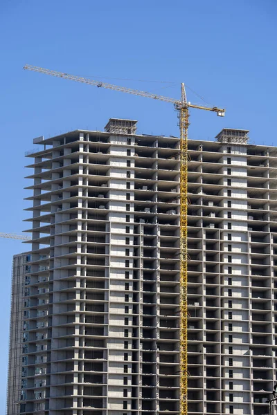 Construção de um edifício alto com guindaste. O guindaste de construção e o edifício contra o céu azul . — Fotografia de Stock