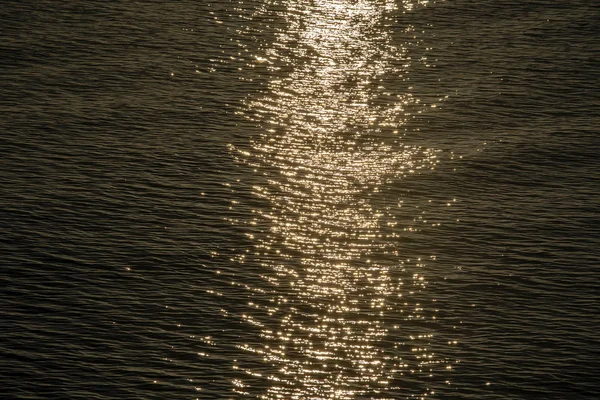 Reflexão do pôr do sol brilha em pequenas ondulações de onda de água do mar — Fotografia de Stock