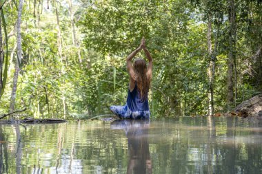 Derin tropikal yağmur ormanlarında çağlayan şelale turkuaz su yakınında yoga yapan güzel kadın, ada Koh Phangan, Tayland