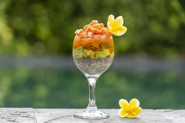Budín de semillas de chía con papaya, maracuyá, mango y aguacate en un vaso para el desayuno en el fondo de la piscina de agua, primer plano. El concepto de alimentación saludable, superalimentos — Foto de Stock