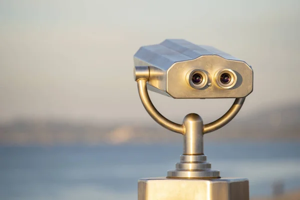 Binocular público en la orilla del mar, de cerca. Visor binocular operado por monedas sobre fondo borroso de atardecer y mar —  Fotos de Stock