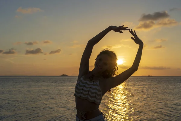 Young beauty girl dansing at tropical beach near sea water at paradise island at sunset. Summer concept. Holiday travel. — Stock Photo, Image