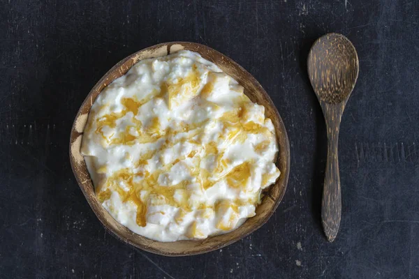 Slices of ripe sweet yellow mango fruit with white cottage cheese, honey and sour cream in coconut bowl , closeup — Stock Photo, Image