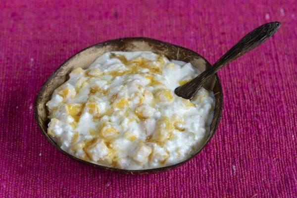 Fatias de manga amarela doce madura com queijo cottage branco, mel e creme de leite em tigela de coco, close-up — Fotografia de Stock