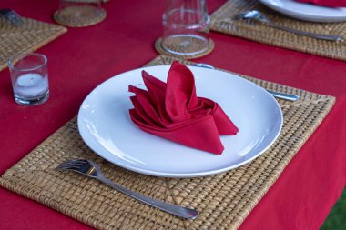 Restoranda çatal, kaşık, beyaz plaka ve kırmızı peçete ile zarif masa ayarı. Düzenlenmiş gümüş ve peçeteler ile güzel yemek masası seti