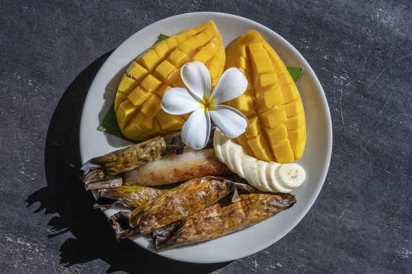 Thai style dessert, yellow mango with banana sticky rice in palm leaves. Yellow mango and sticky rice is popular traditional food of Thailand. Closeup — Stock Photo, Image