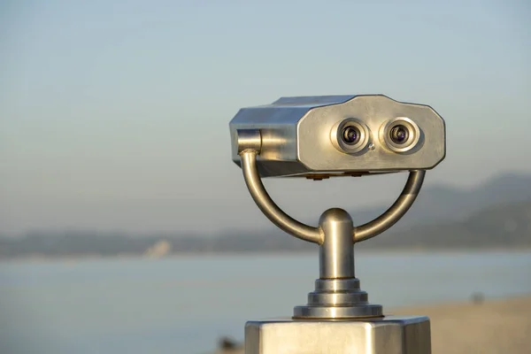 Binocular público na costa do mar, de perto. Moeda operado visualizador binocular no fundo turvo do pôr do sol e do mar — Fotografia de Stock