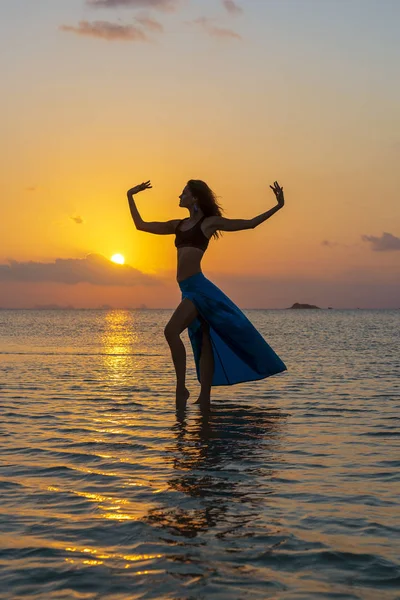 Junges Schönheitsmädchen, das am tropischen Strand auf dem Meerwasser der Paradiesinsel bei Sonnenuntergang tanzt. Sommerkonzept. Urlaubsreise. — Stockfoto