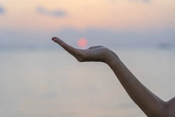 Silhouet van jong meisje in de hand houden van de zon tijdens zonsondergang, close-up — Stockfoto