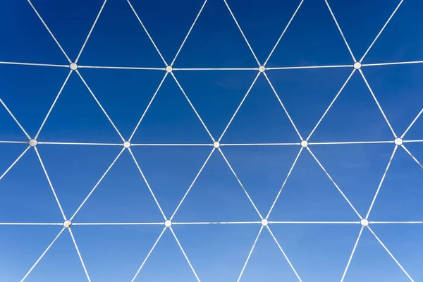 在蓝天背景上呈几何形状的金属白色晶格 — 图库照片
