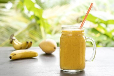 Tropikal meyve ile Smoothie: mango, muz, ahşap masada bir cam kavanozda ananas. Sağlıklı bir yaşam tarzı kavramı. Yakın çekim