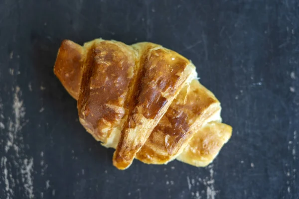 Croissant fresco em um fundo de mesa de madeira preta. Vista superior — Fotografia de Stock