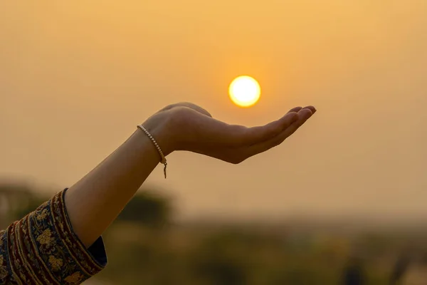 Silueta de niña sosteniendo el sol en la mano durante la puesta del sol, primer plano —  Fotos de Stock