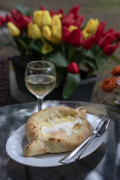 Adjarian khachapuri in restaurant. Open bread pie with cheese and egg yolk. Yummy georgian cuisine.