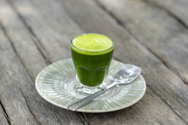 Eski ahşap masa arka planda cam taze kepekli Buğday çim suyu doğal içecek. Organik sağlıklı organik yeşil detoks suyu