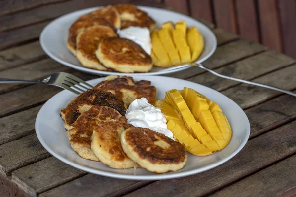 Bolos de queijo com manga e creme azedo. Sobremesa gostosa, de perto — Fotografia de Stock