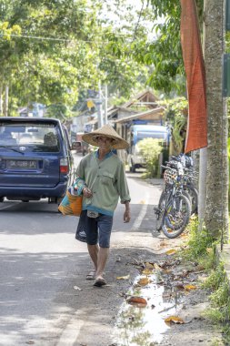 Hasır şapkalı Endonezyalı bir adam Ubud, ada Bali, Endonezya kentinde yerel bir pazara yolda