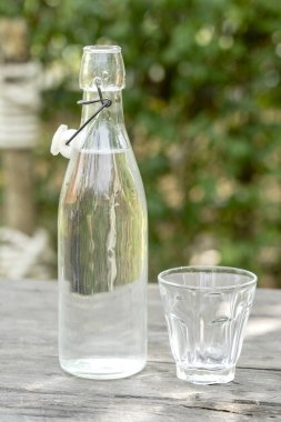 Ahşap masada su ile şişe ve cam