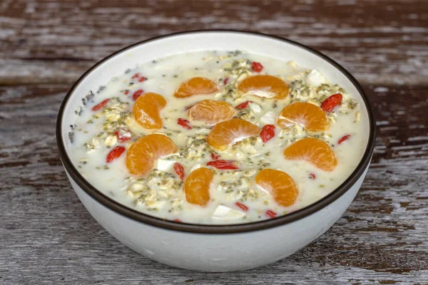 Granola, yoğurt, fındık, Goji çilek, Chia tohumları ve mandalina taze kahvaltı. Ahşap bir arka planda kase meyve ve çilek ile muesli — Stok fotoğraf