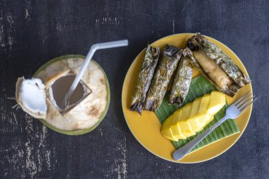 Tay tarzı tatlı, palmiye yapraklarımuz yapışkan pirinç ile sarı mango. Sarı mango ve yapışkan pirinç Tayland popüler geleneksel tatlı.