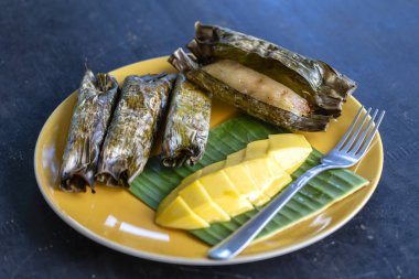 Tay tarzı tatlı, palmiye yapraklarımuz yapışkan pirinç ile sarı mango. Sarı mango ve yapışkan pirinç Tayland popüler geleneksel tatlı.