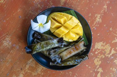 Tay tarzı tatlı, palmiye yapraklarımuz yapışkan pirinç ile sarı mango. Sarı mango ve yapışkan pirinç Tayland popüler geleneksel tatlı.