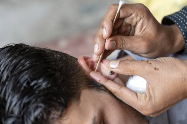 Hintli adam, yerel pazarda sokakta çalışan bir kulak temizleyicisi, Rishikesh India. Birkaç rupi için, diğer adam kulaklarını temizletti..
