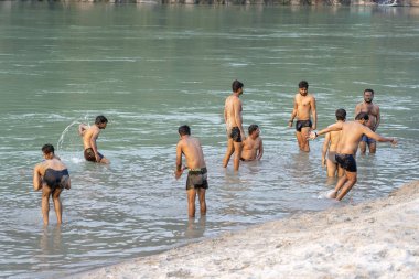 Hindistan'ın Rishikesh şehrinde ganj nehrinin kutsal sularında yüzen Hintli çocuklar.