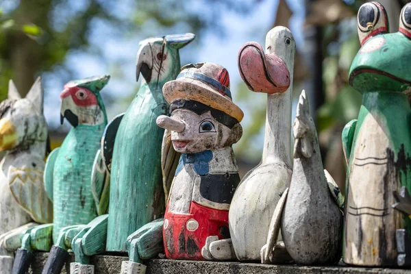 Old wooden souvenirs toys on the stone fence near the doll shop in Ubud, Bali island, Indonesia. Closeup