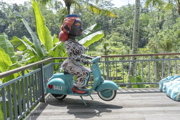 Figura de una mujer de piel oscura sentada en una motocicleta Vespa en una cafetería tropical cerca de terrazas de arroz de Tegallalang en Bali, Indonesia — Foto de Stock