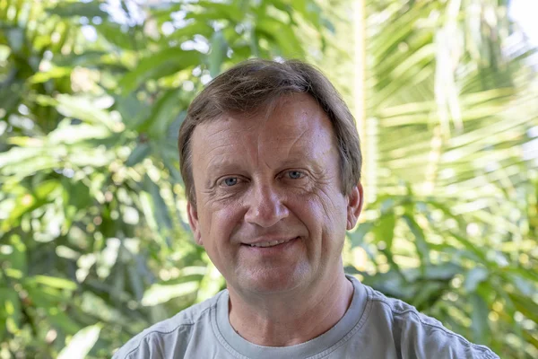 Portrait of a middle aged man resting on a background of green leaves, close up — Stock Photo, Image