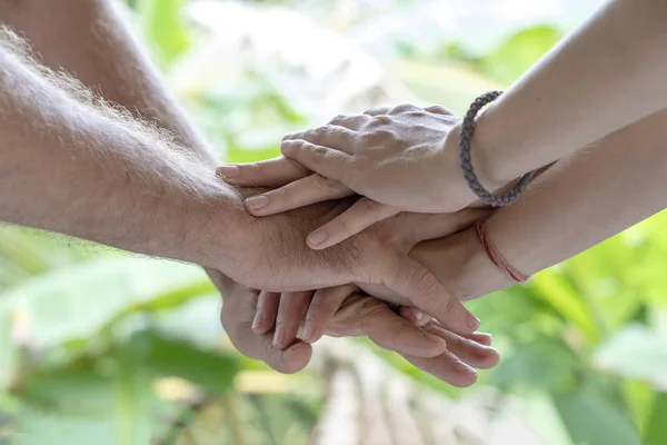 Many hands getting together in the center of a circle. Close up outdoor shot