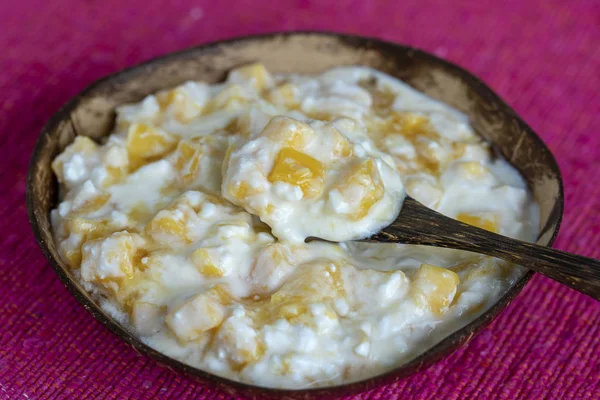 Rebanadas de fruta amarilla madura de mango dulce con requesón blanco, miel y crema agria en un tazón de coco, primer plano — Foto de Stock