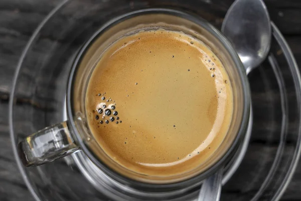 Стеклянная чашка горячего кофе эспрессо на доске, крупный план, вид сверху — стоковое фото