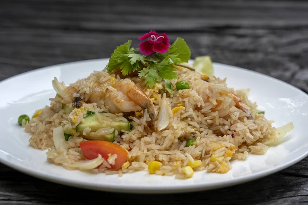 Gebakken rijst met garnalen en groenten in een witte schaal op een oude houten tafel, close-up. Thais eten, Thaise keuken — Stockfoto