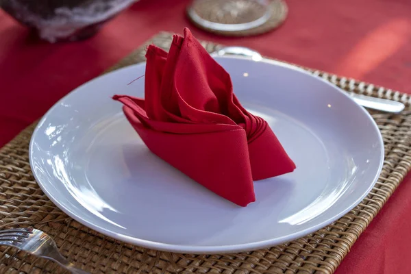 Elegante tafel setting met vork, lepel, witte plaat en rode servet in restaurant. Mooie eettafel set met gearrangeerd zilverwerk en servetten — Stockfoto