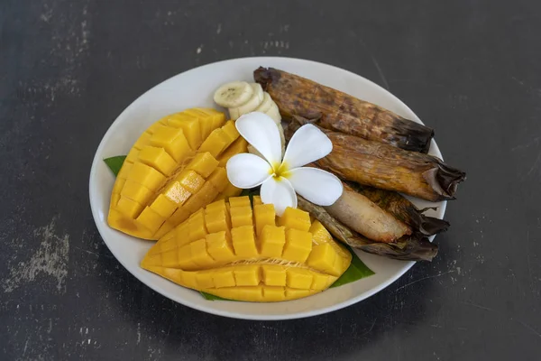 Thai style dessert, yellow mango with banana sticky rice in palm leaves. Yellow mango and sticky rice is popular traditional food of Thailand. Closeup — Stock Photo, Image