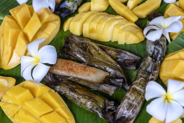 Tay tarzı tatlı, palmiye yapraklarımuz yapışkan pirinç ile sarı mango. Sarı mango ve yapışkan pirinç Tayland popüler geleneksel tatlı.