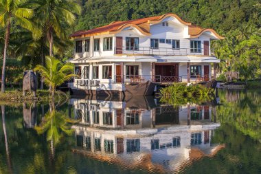 Yeşil palmiye ağaçları olan ormanda, denizin yanında bir gemi şeklinde tropikal bir ev. Tayland 'da lüks bir sahil beldesinde. Doğa ve seyahat kavramı