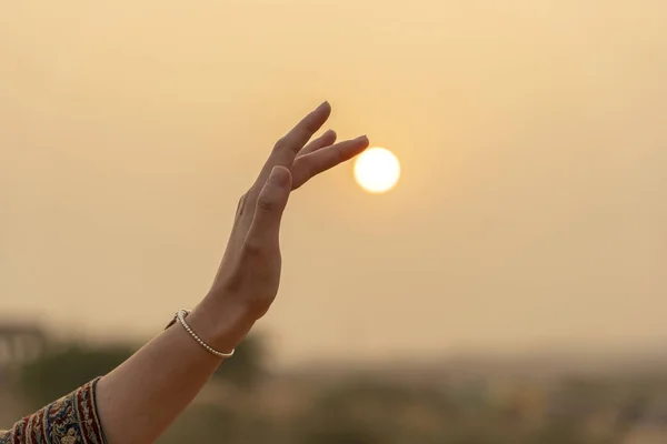 Silhouet van jong meisje houdt de zon in de hand tijdens zonsondergang, close-up — Stockfoto