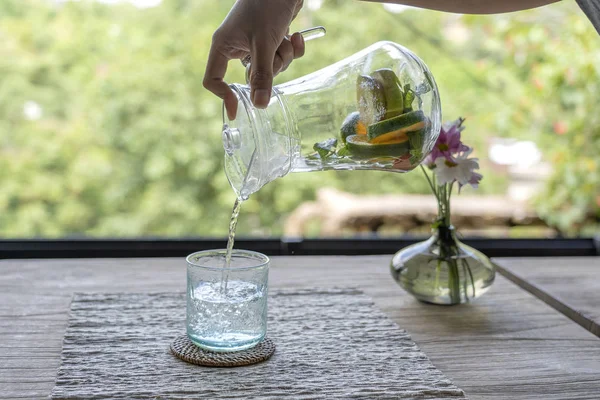 Un serveur dans un restaurant verse de l'eau de fruit d'une carafe dans un verre — Photo