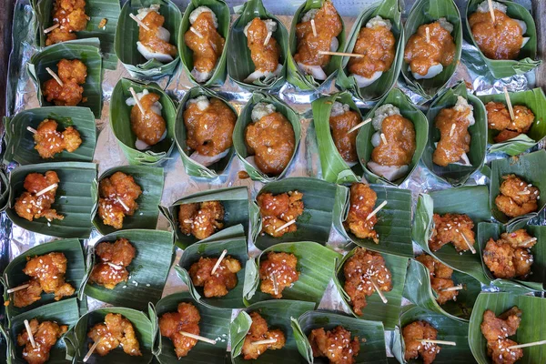 Spuntino tradizionale indonesiano in foglie di palma verde. Chiudete. Asiatico cibo sfondo, tavolo a buffet — Foto Stock